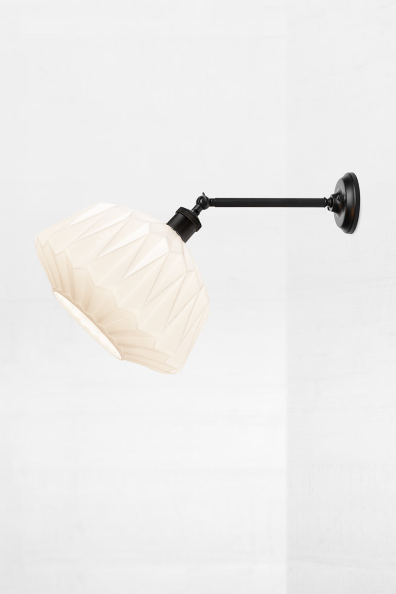 geometric opal glass shade on a long black straight arm wall sconce with swivel lampholder