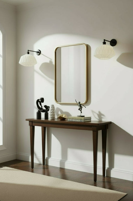 Two opal glass shades with geometric patterns on black wall sconces over a hall table. 