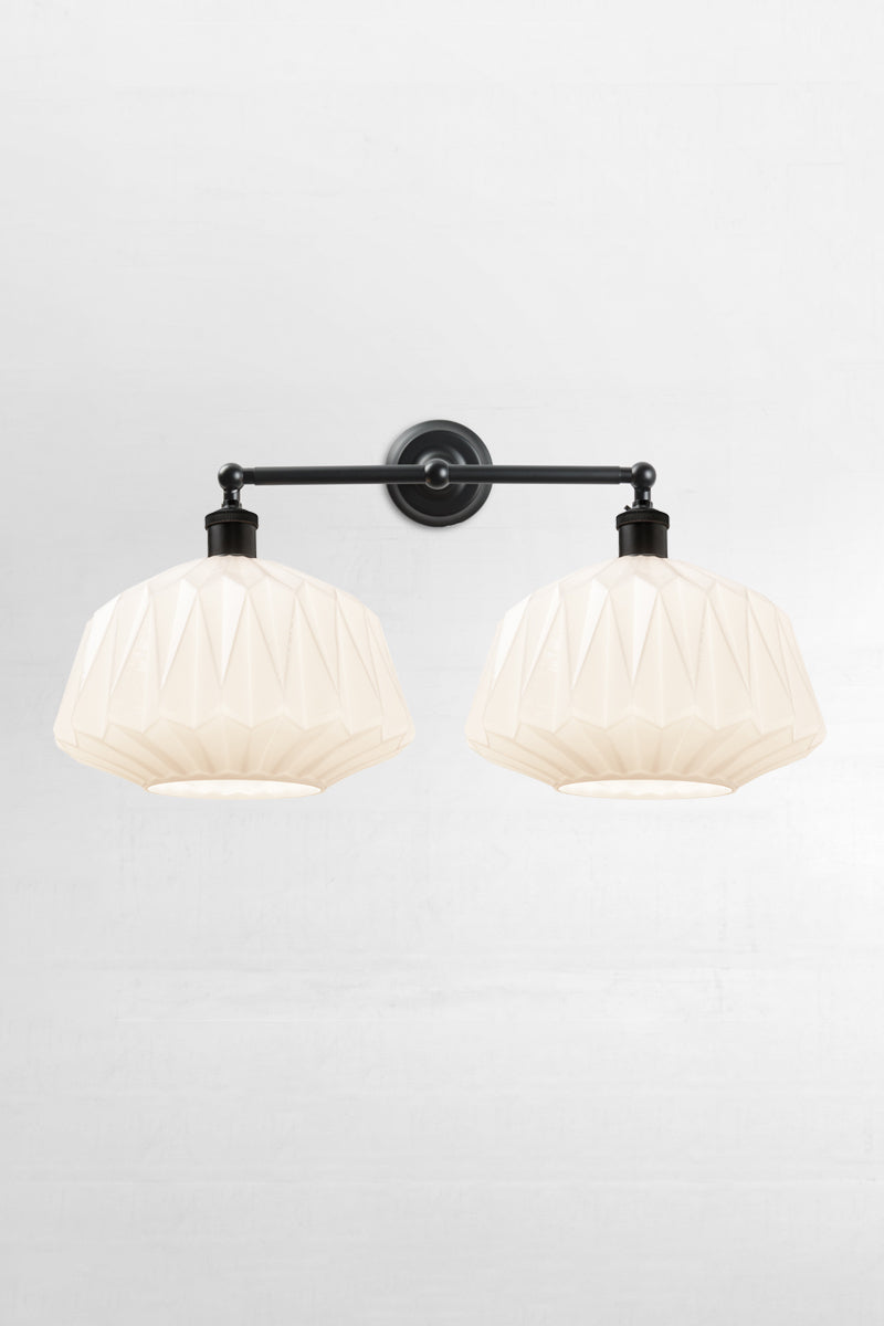 Two opal glass shades with geometric design on a black double swivel wall sconce 