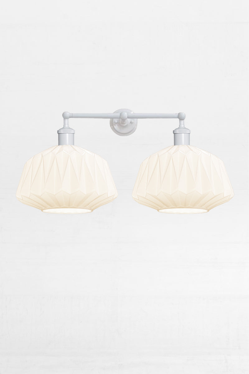 Two opal glass shades with geometric design on a white double swivel wall sconce 