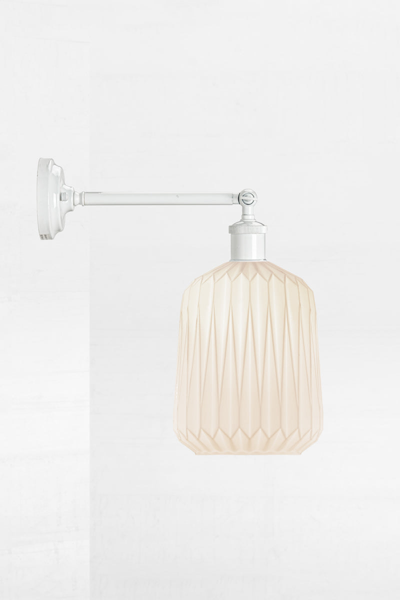 Wall sconce with a long white straight arm holding an opal glass shade with geometric detailing. 