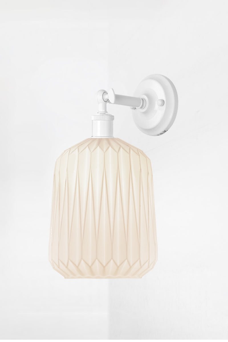 Wall sconce with a short white straight arm holding an opal glass shade with geometric detailing. 