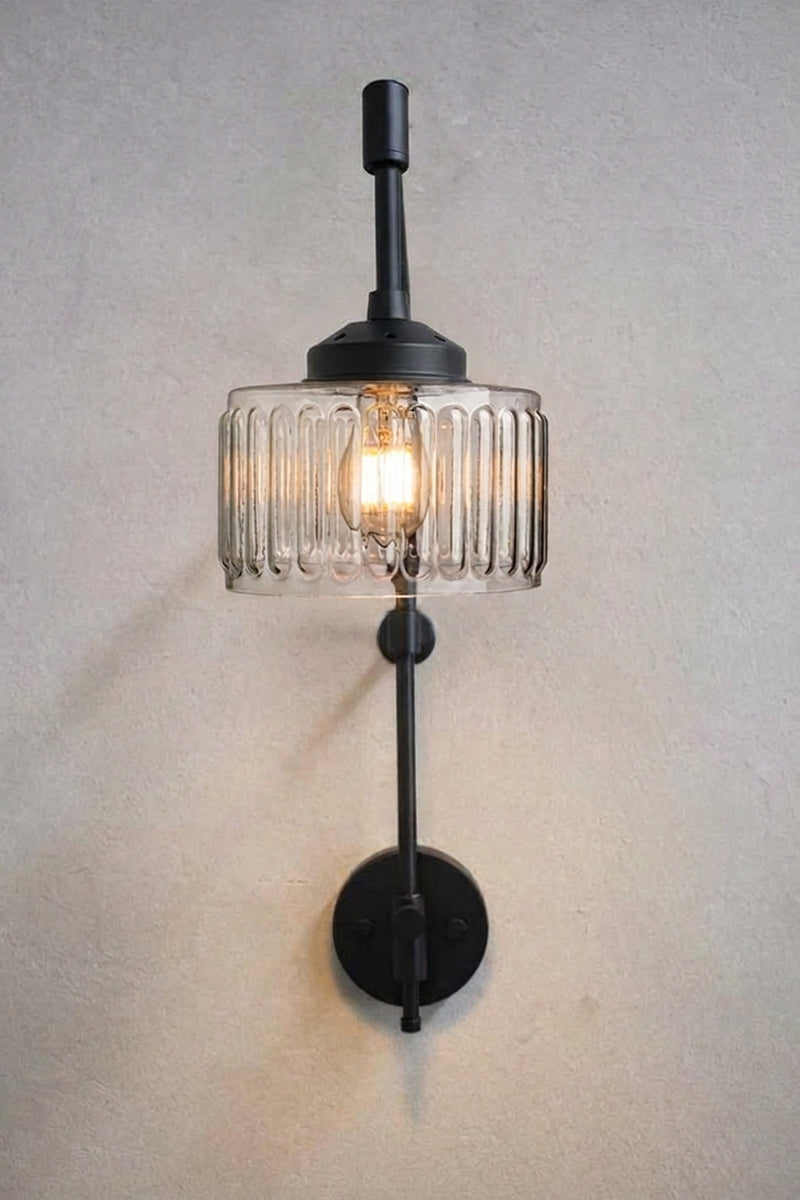 Front view of Capri Glass Wing Arm Wall Lamp with illuminated clear fluted glass shade and matt black fixture