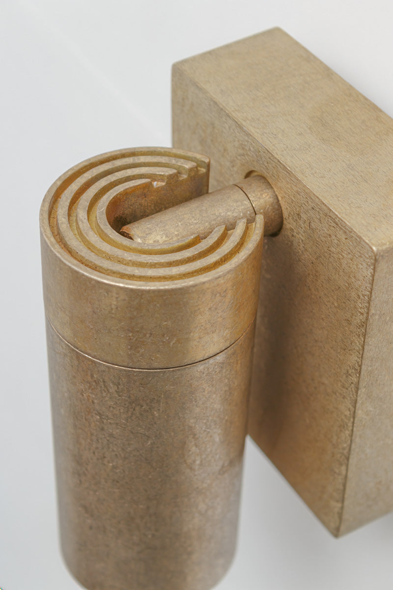 Close up of an antique brass wall spotlight highlighting the brushed metal finish and cylindrical shade.