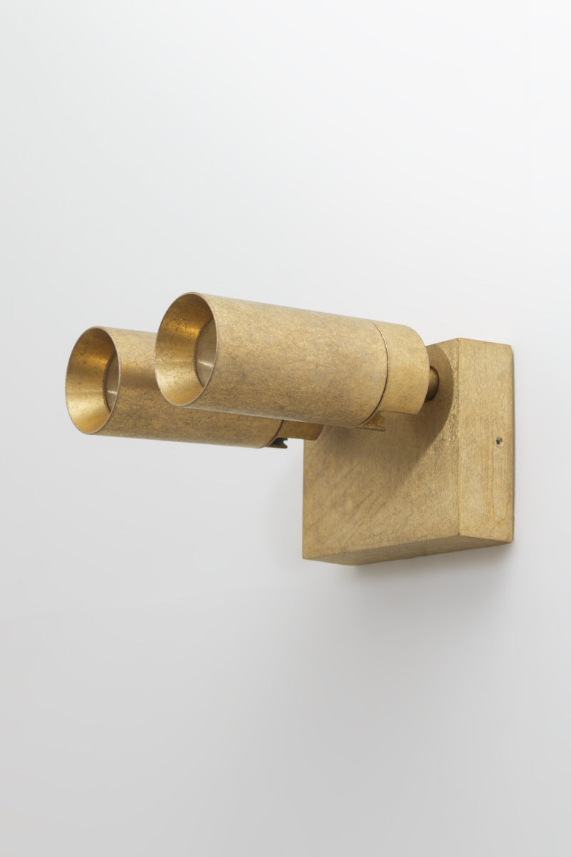Brass wall-mounted light fixture with adjustable heads on a white outdoor wall