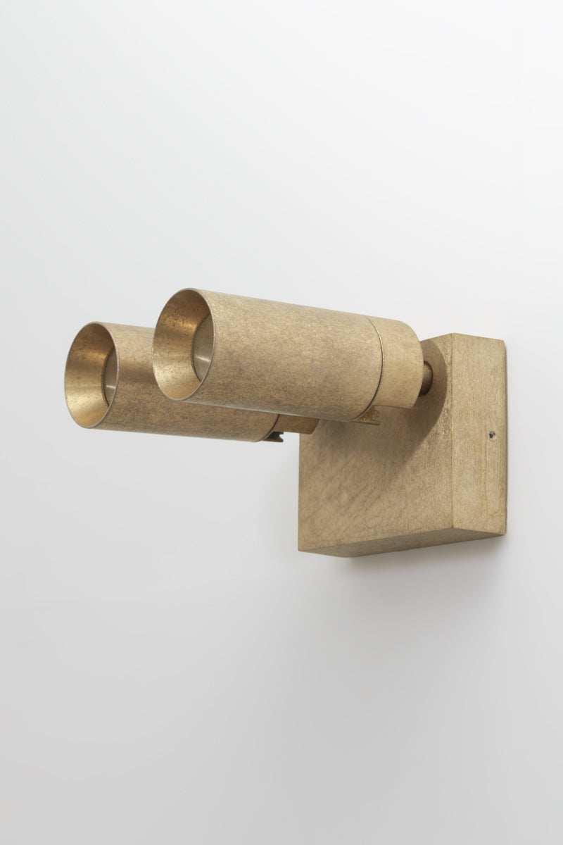 Brass wall-mounted light fixture with adjustable heads on a white outdoor wall