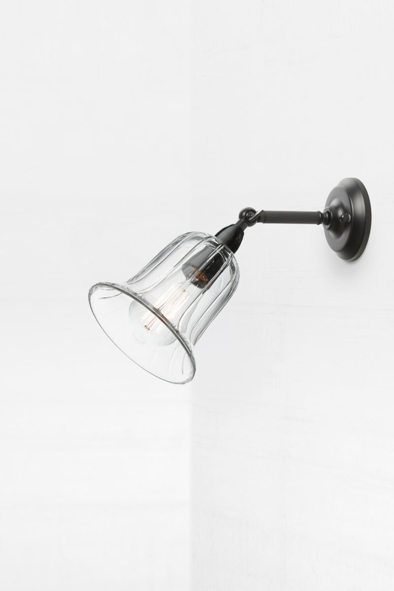 IP44 black exterior short, straight arm wall sconce that is tilted outwards holding the clear glass shade. 