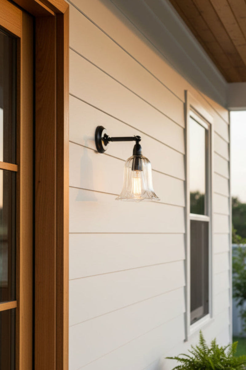 Long strat arm ajustable wall sconce in black with a bell shaped clear glass shade as an entry light on a modern farm house style home