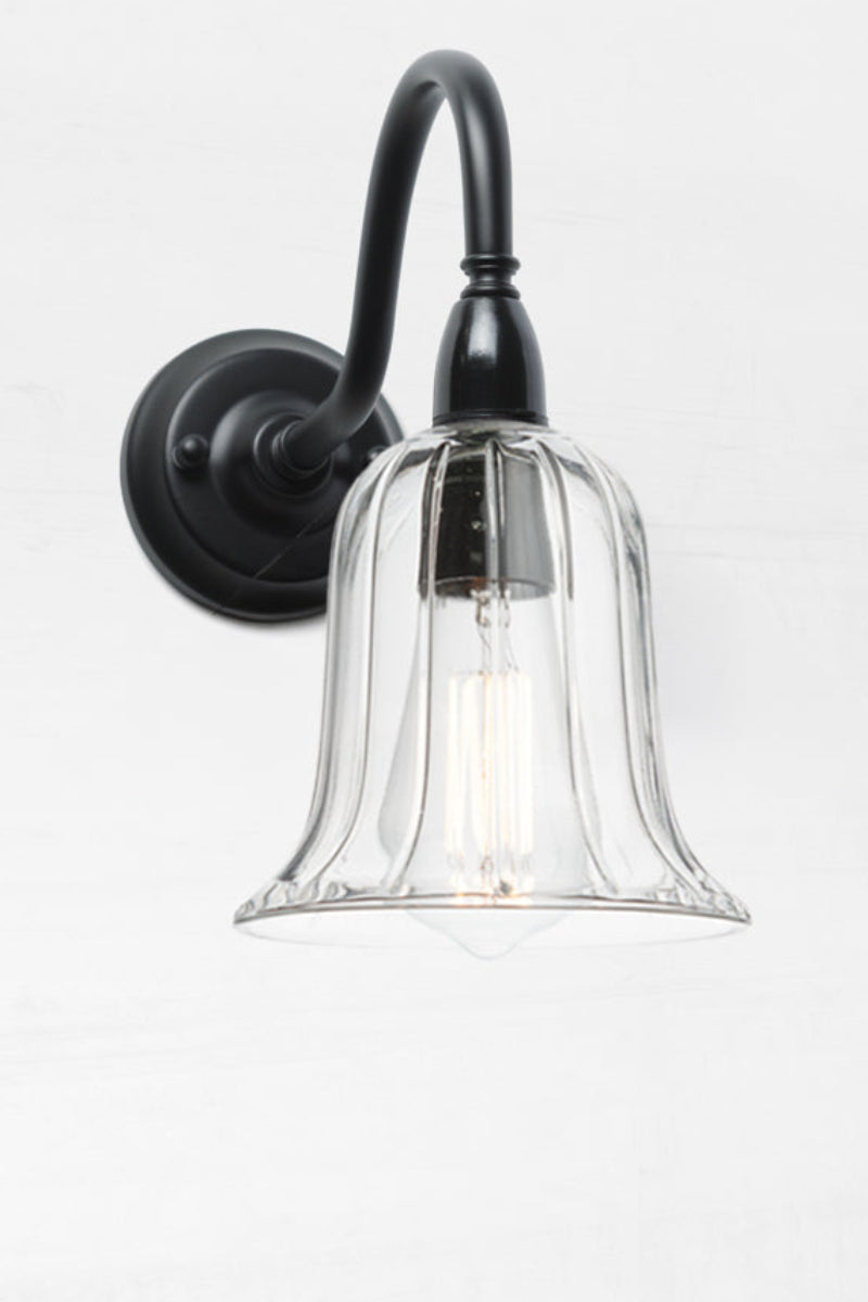 Clear glass shade with subtle reeded detailing on an IP44 black exterior gooseneck wall sconce. 