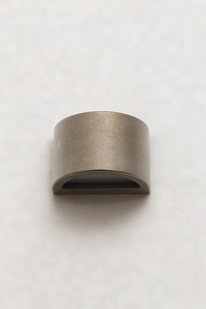 A compact curved step light in Age Brass that casts light downward
