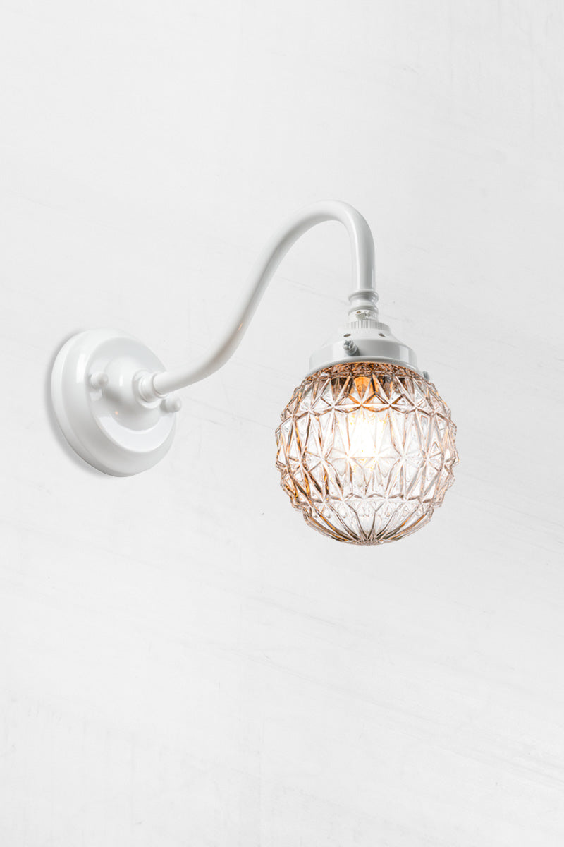 Glass ball shade with diamond cut detailing paired with a whitegooseneck wall arm.