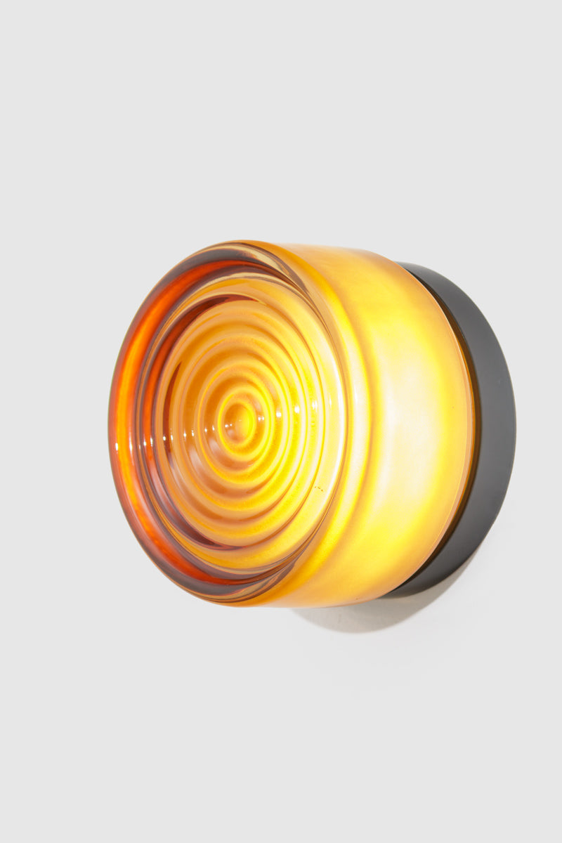 Amber LED glass wall light mounted on a white wall with concentric glass detailing.