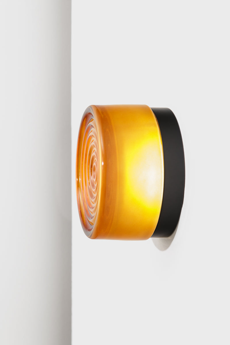 Side profile of the amber LED glass wall light showing the layered glass shade and black mounting base.