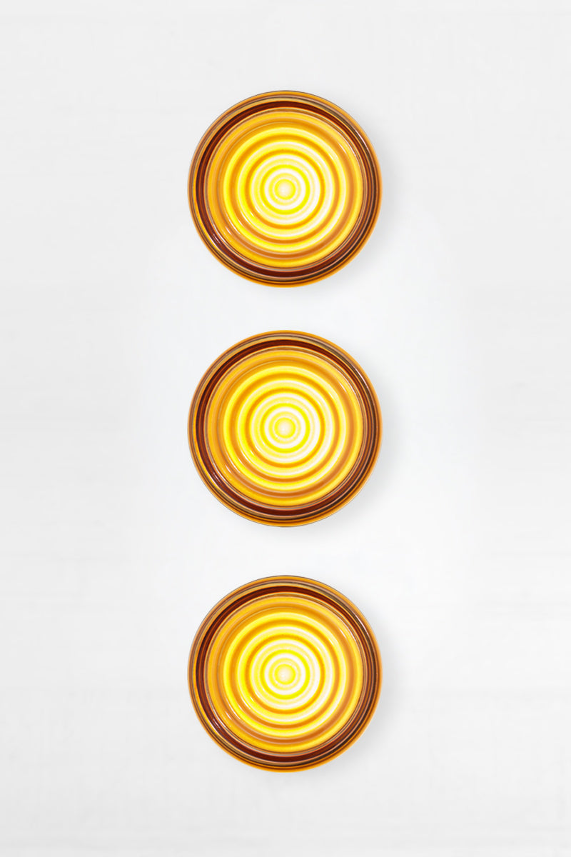 Bundle of three amber LED glass wall lights shown front-on with concentric glass detailing.