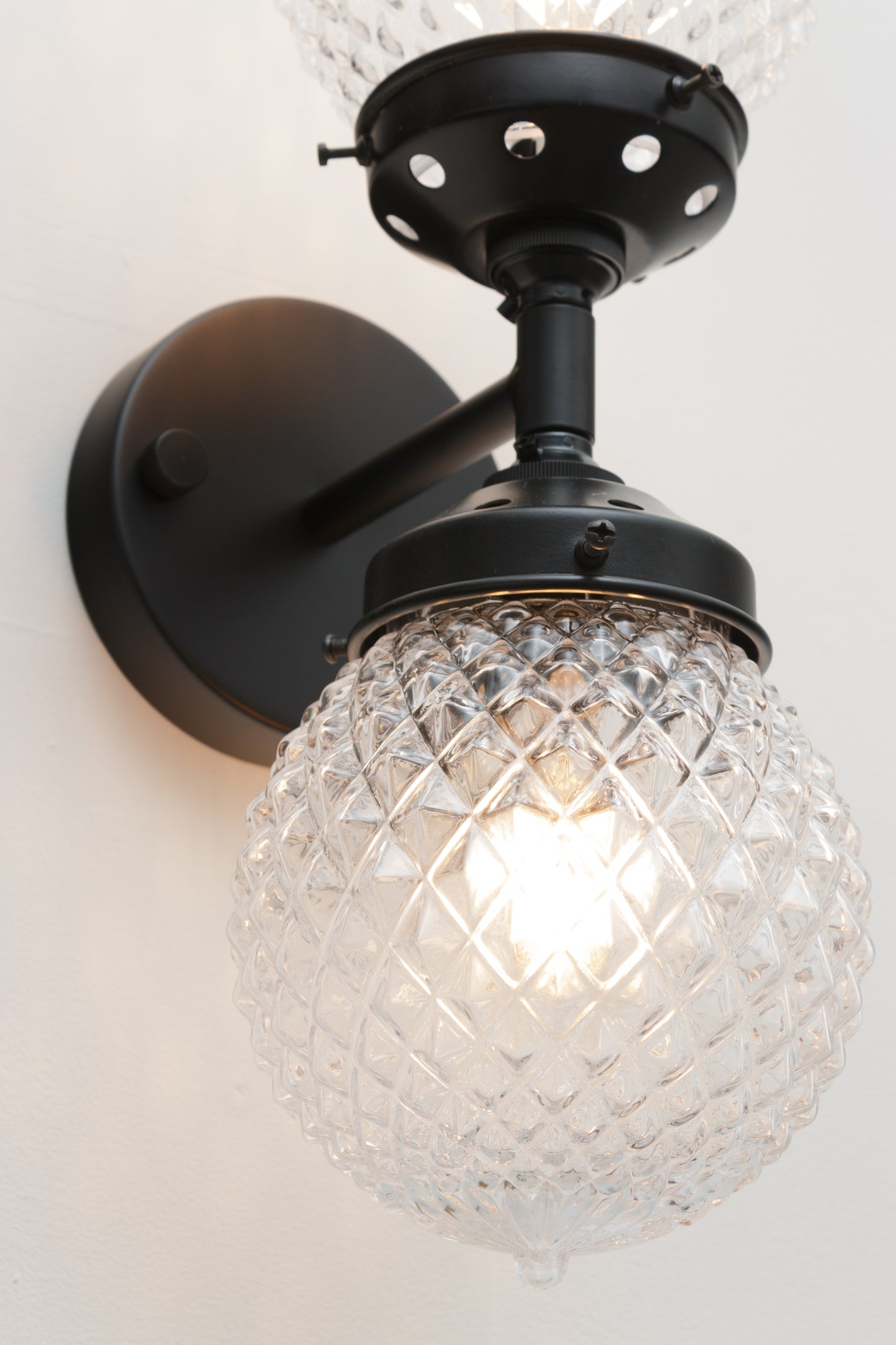 Clear glass vintage inspired glass wall light characterised by a picturesque textured pattern.