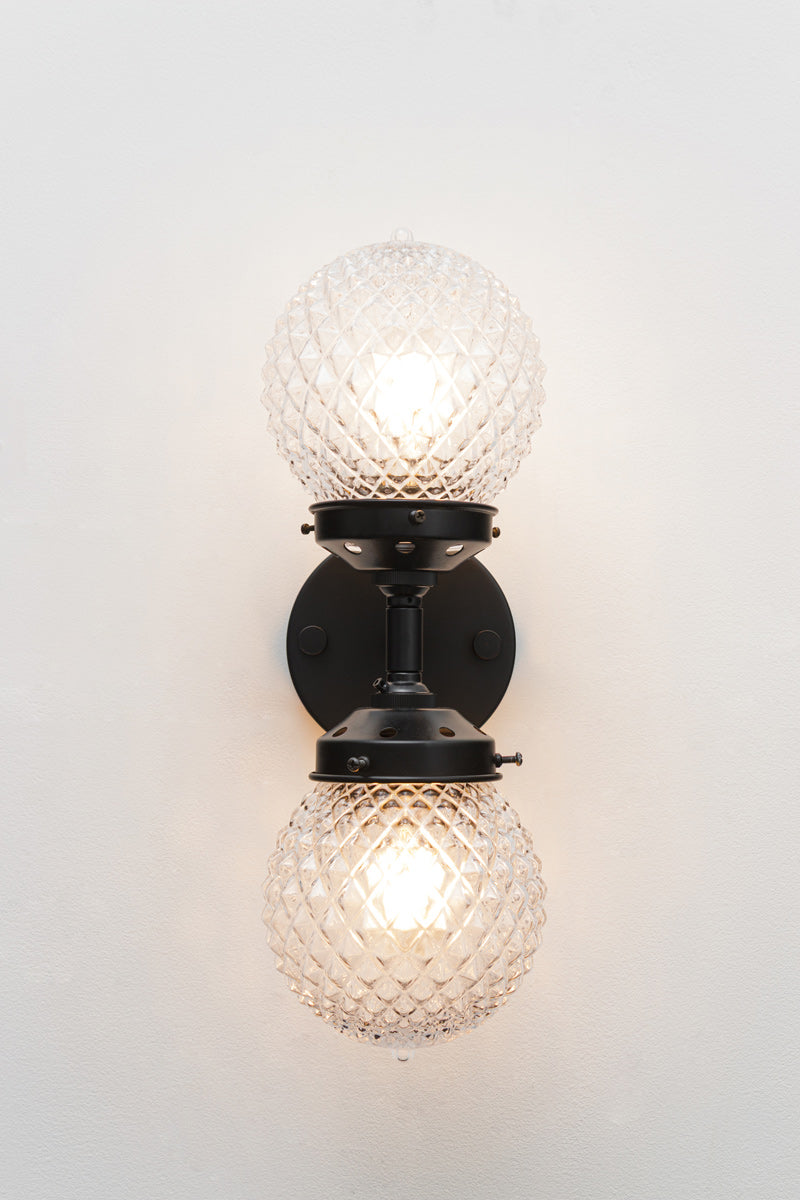 Two clear glass orbs with a vintage-inspired diamond cut design on double wall sconce