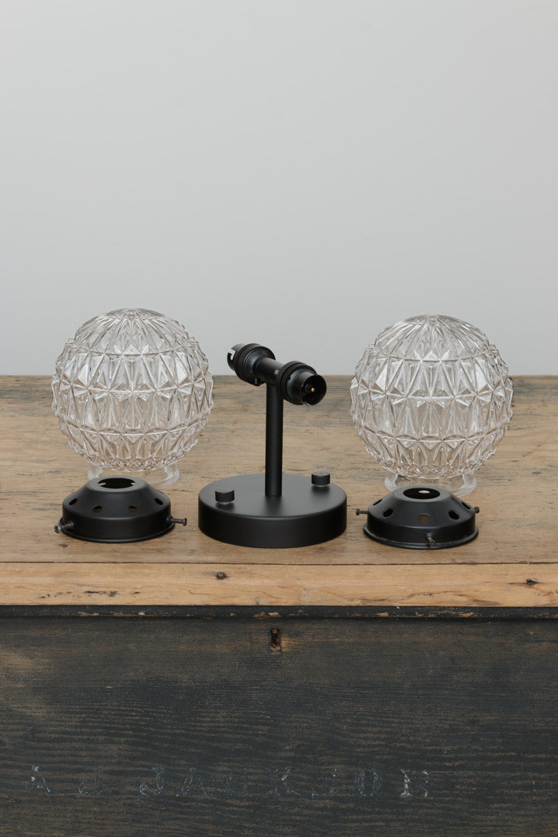 trunk shot of Two clear glass orbs and steel dual wall sconce