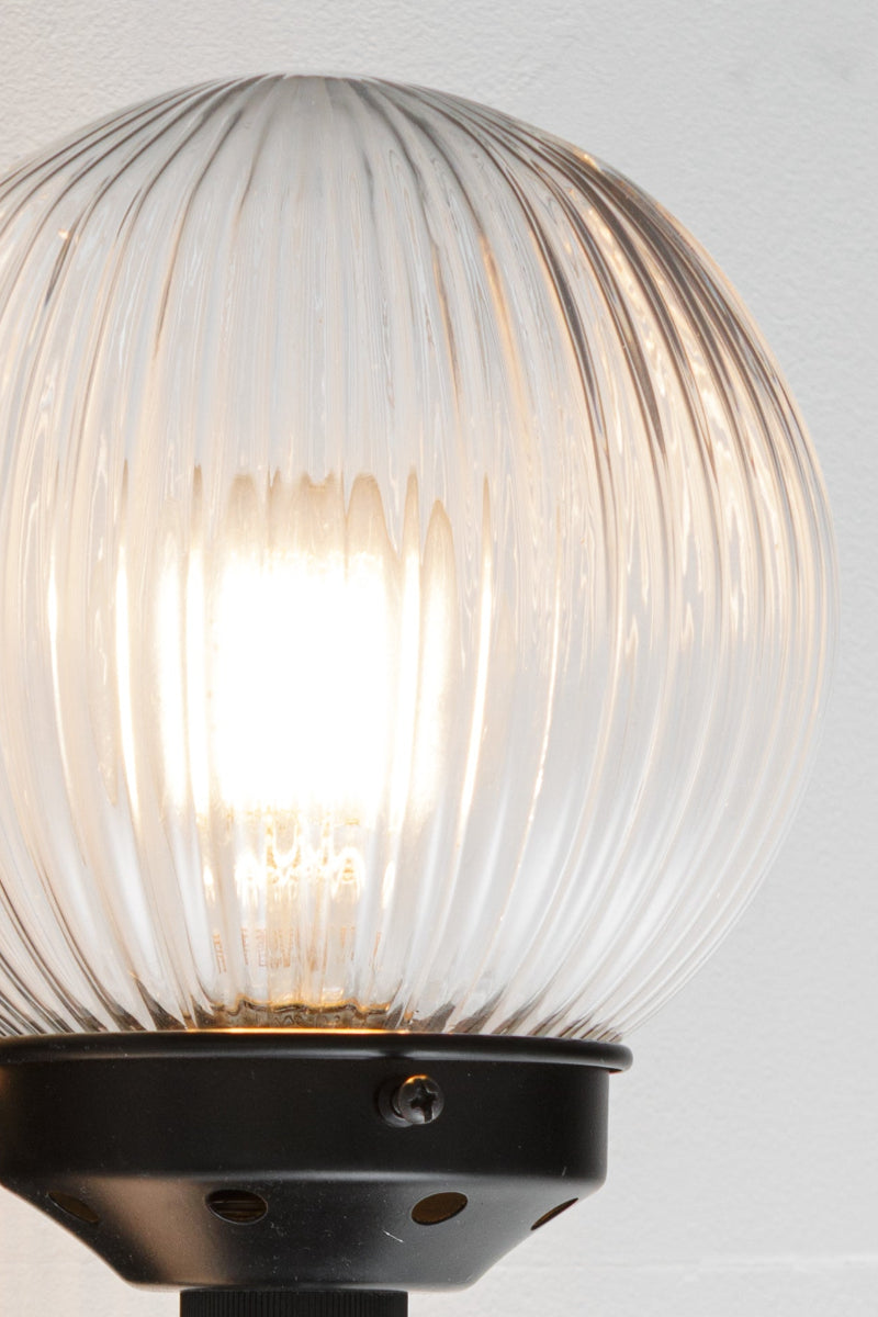 Close up of the Black five lamp linear chandelier with clear reeded glass ball shades. 