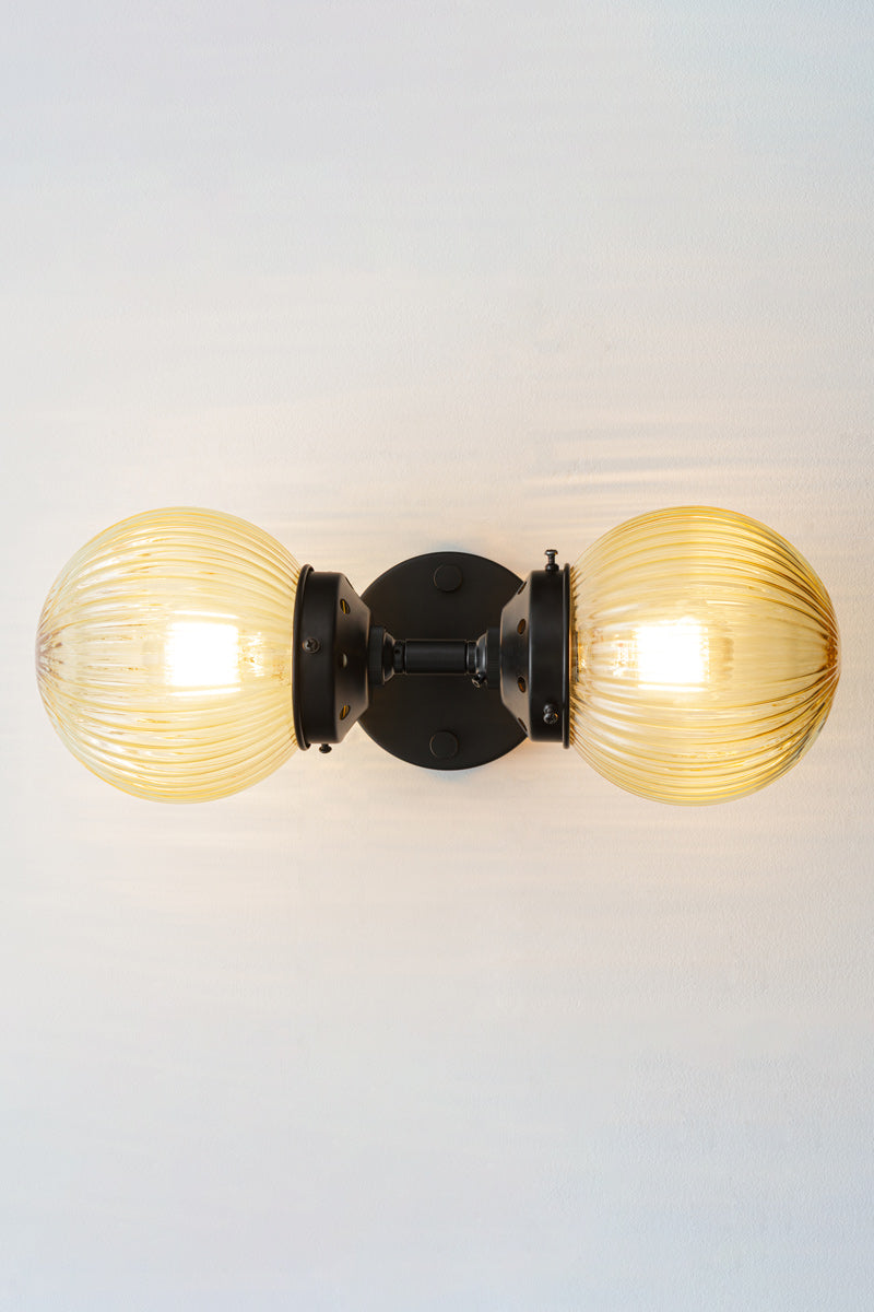 Dakota Reeded Glass Double Light Wall Sconce sitting horizontally with amber shades