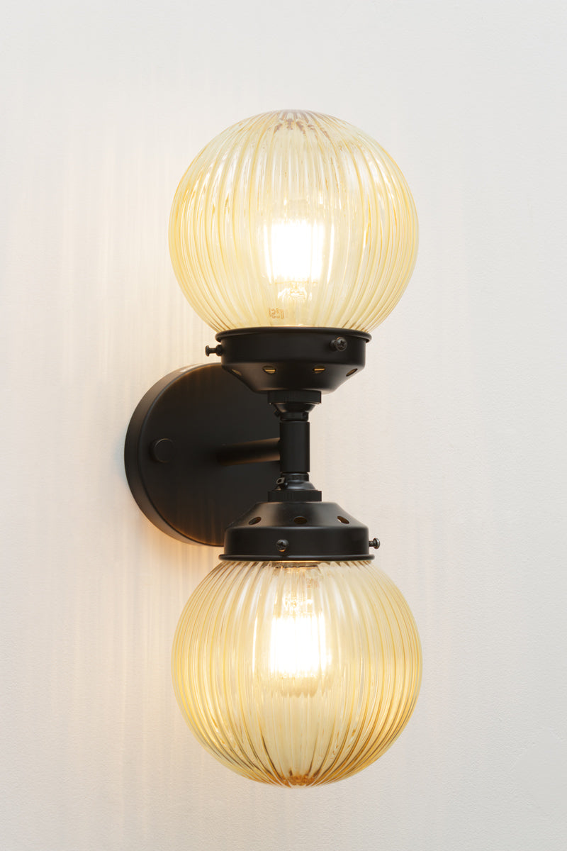 Dakota Reeded Glass Double Light on a black Wall Sconce with amber shades on each end