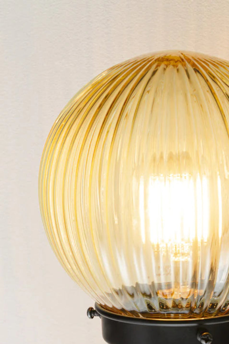 Close up of the Black five lamp linear chandelier with amber reeded glass ball shades. 