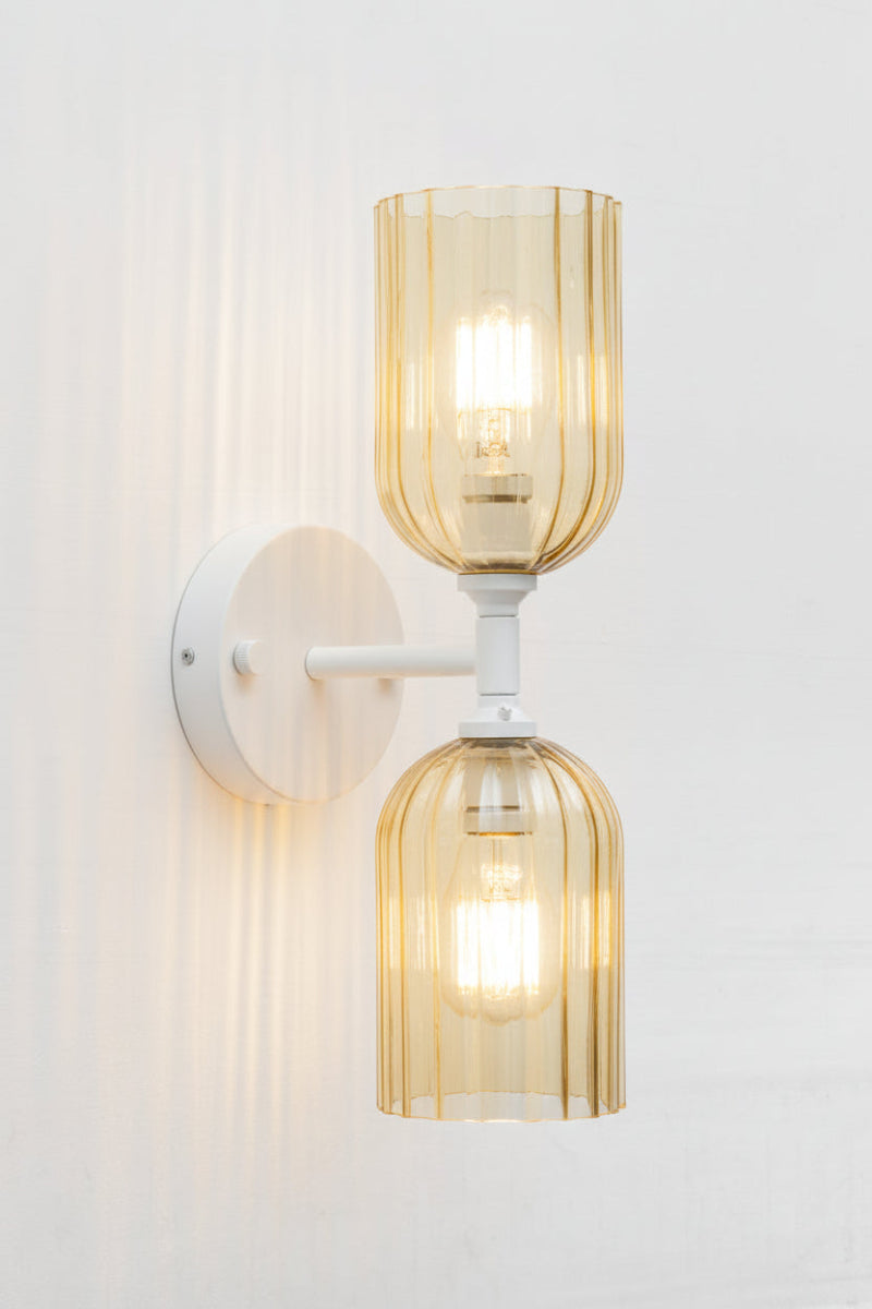 White double wall sconce paired with two eloganted amber glass shades with fluted detailing. 