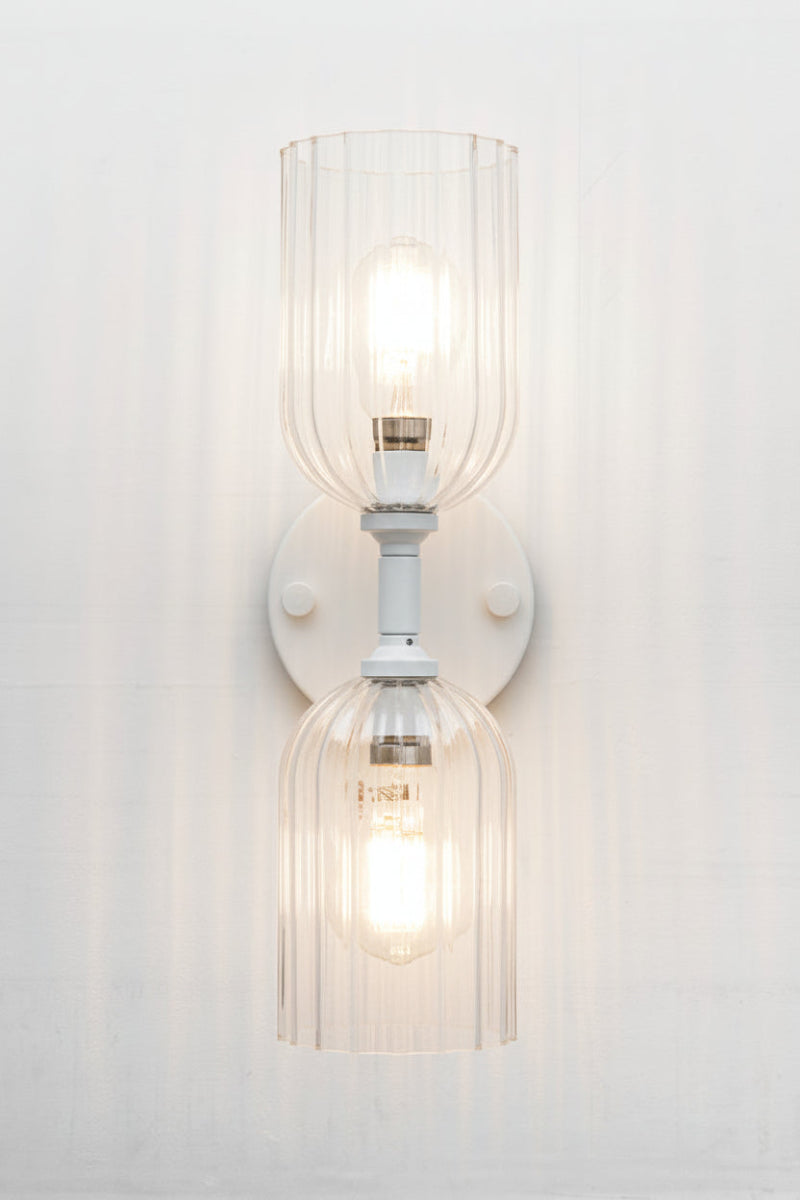 White double wall sconce paired with two eloganted clear glass shades with fluted detailing. 