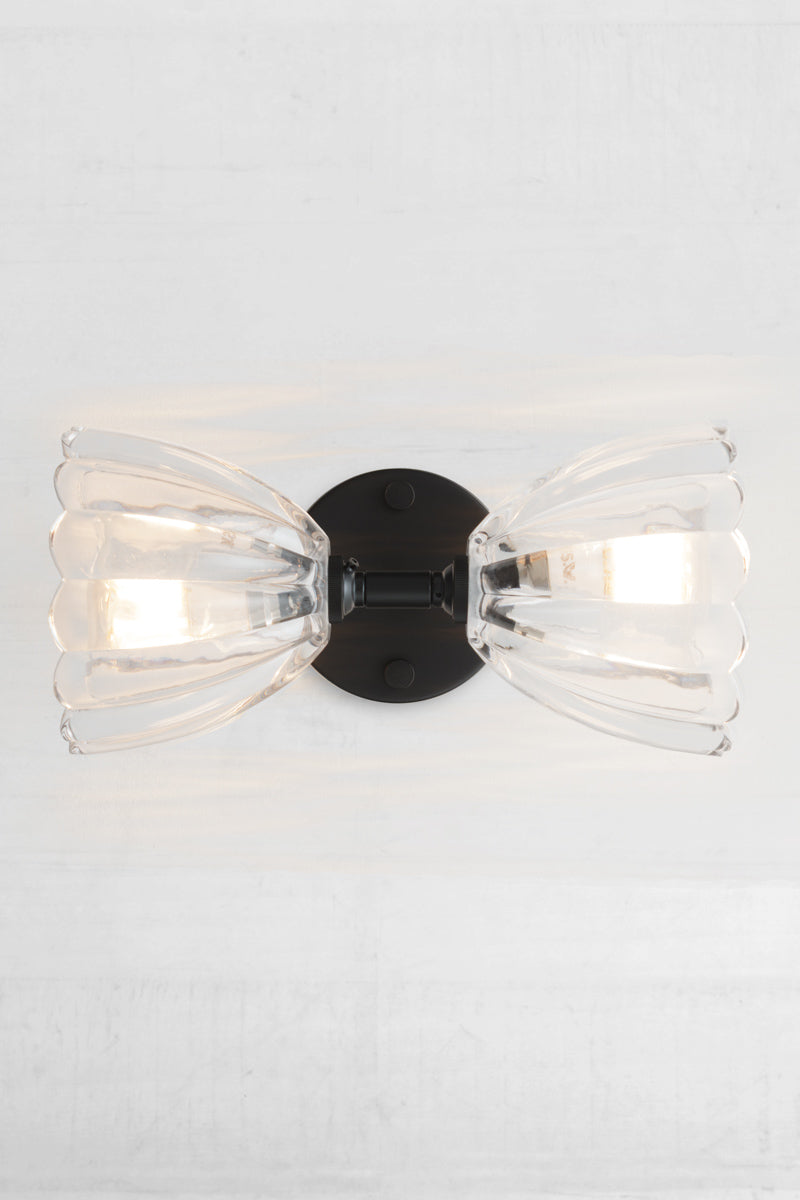 Showcasing a sideways installation of the black double wall light with two clear glass shades. 