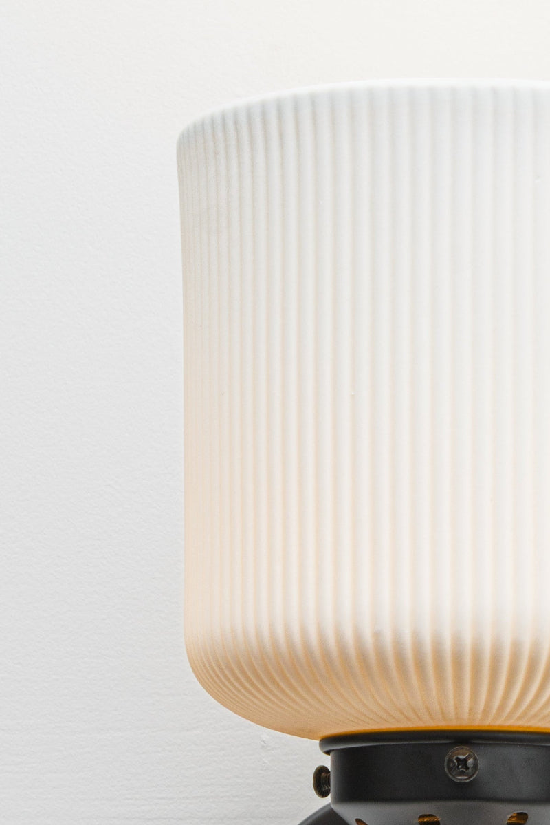 Close up of the white ceramis shade with reeded detailing and a black gallery. 