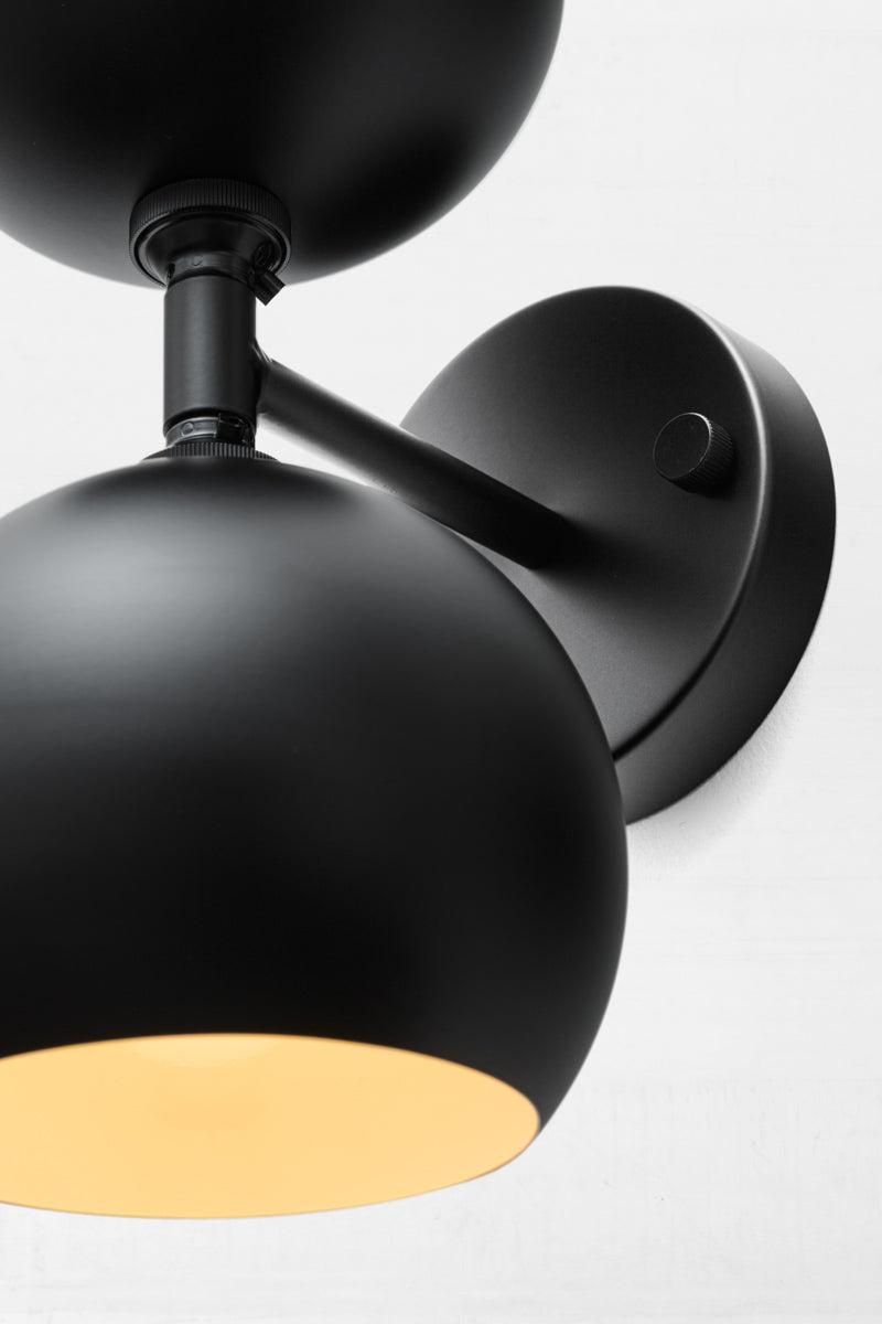 Close up of the black double wall sconce with two steel bulb shades in black.