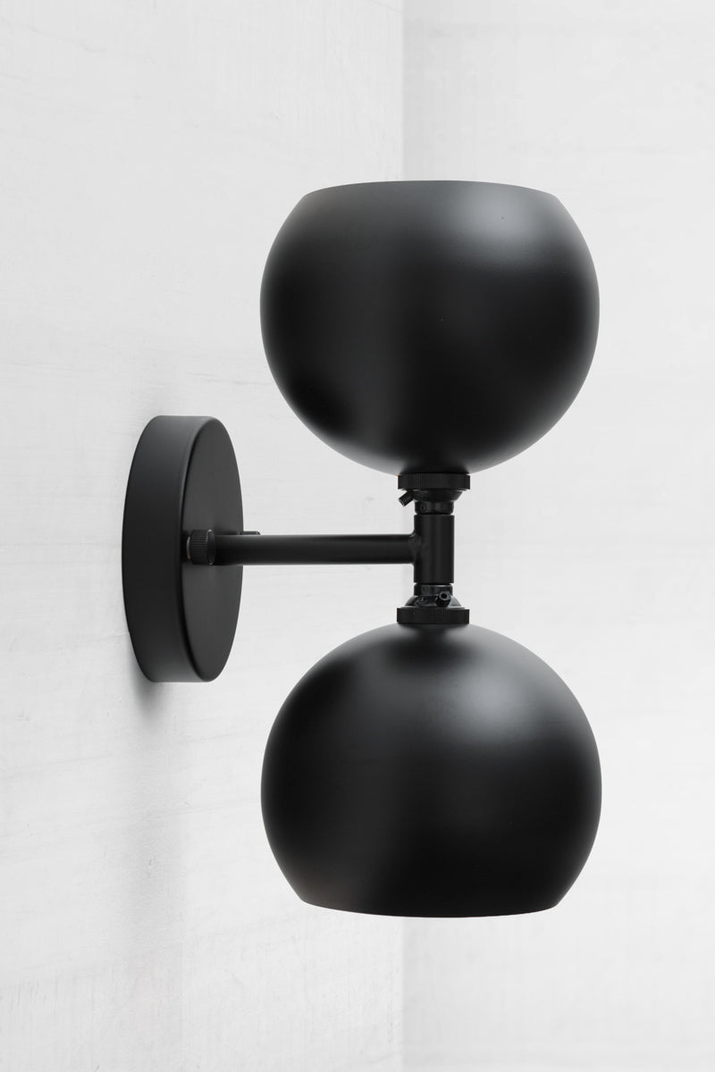 Black double wall sconce with two steel bulb shades in black.