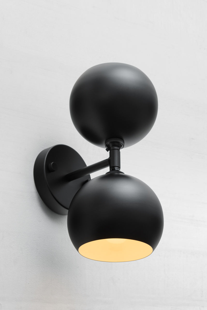 Black double wall sconce with two steel bulb shades in black, with white inner. 