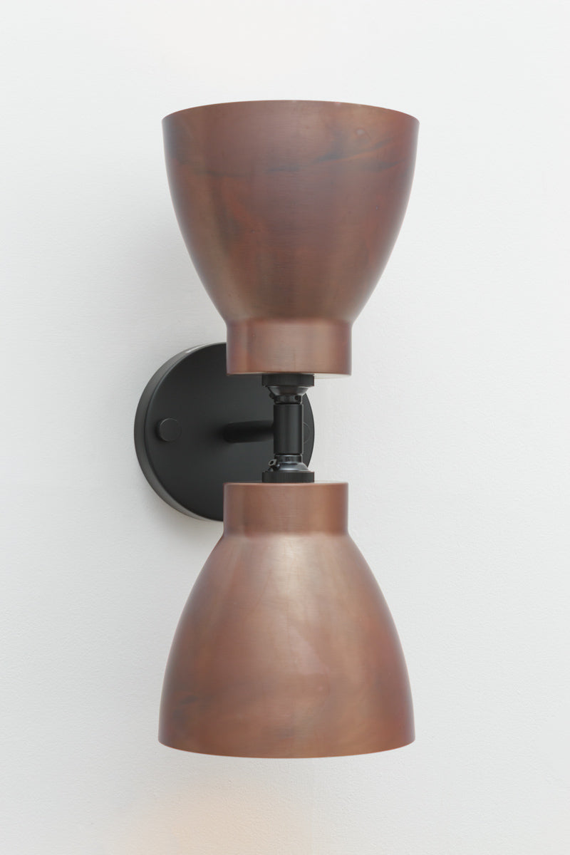 Wall sconce with a black double wall arm with two solid copper bell-shaped shades. 