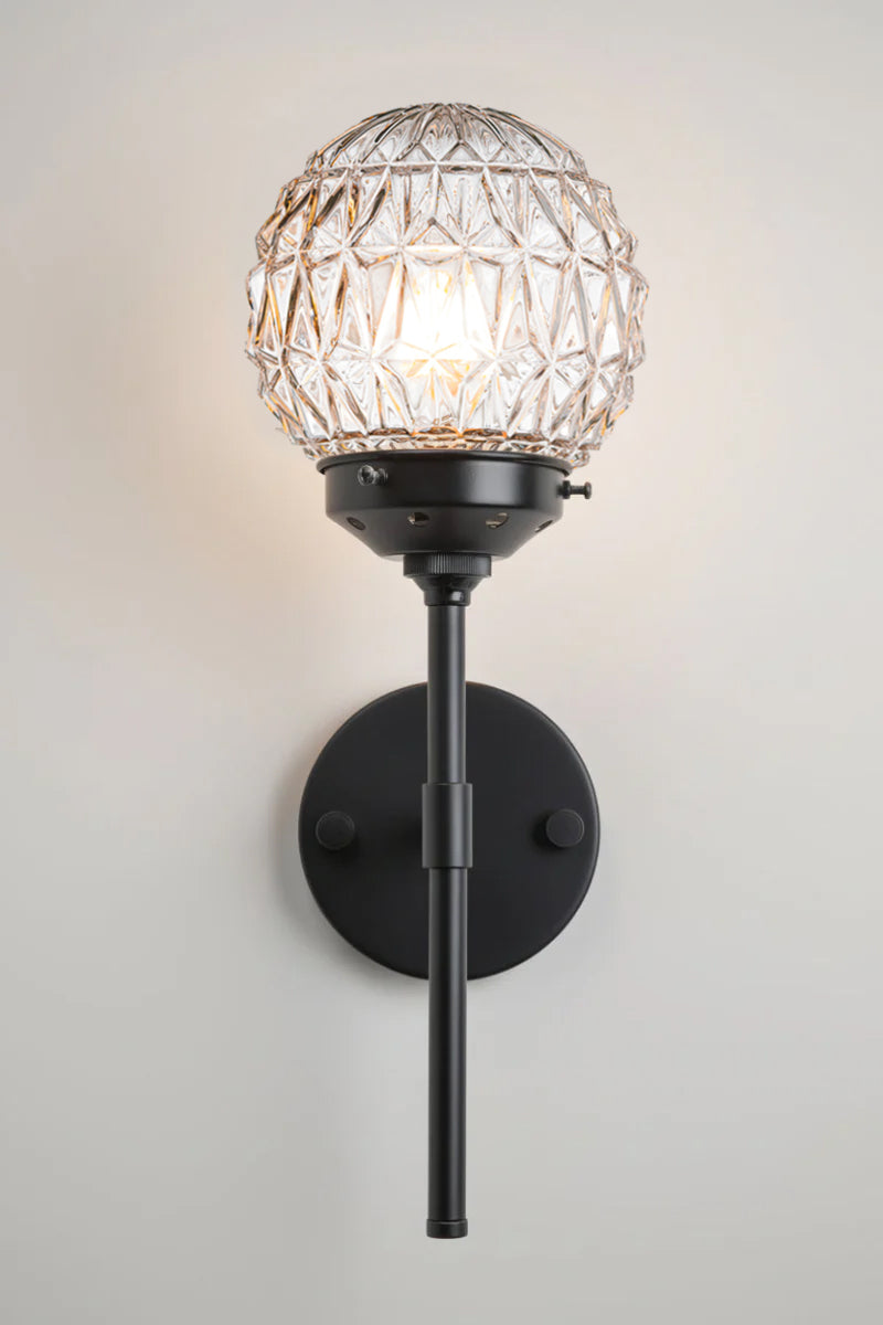 Clear glass ball shades with diamon-cut detailing paired with a black steel stem wall sconce. 