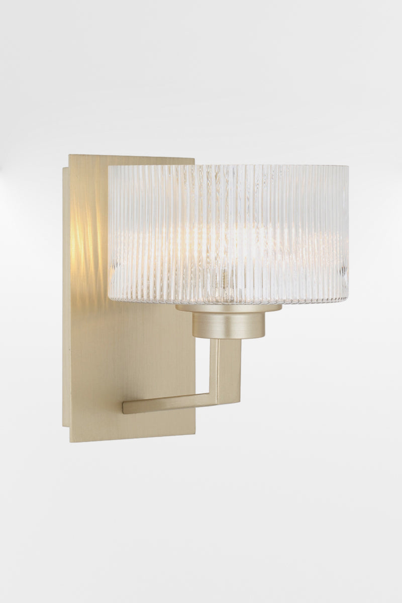 Wall sconce in Antique Silver with a rectangular mount plate and arm, holding a clear reeded cylindrical glass shade.