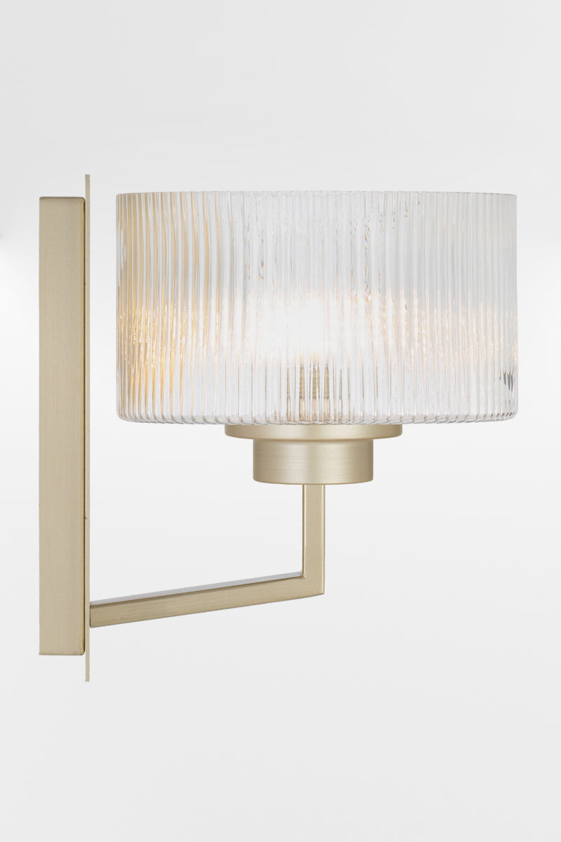Side view of the wall sconce in Antique Silver with a rectangular mount plate and arm, holding a clear reeded cylindrical glass shade.