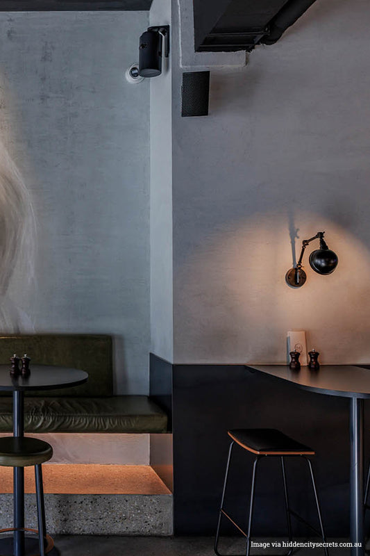 Modern interior of The Metropolitan Hotel with a wall-mounted light fixture,; Gallery Swing Arm Wall Lamp and table, and bench.