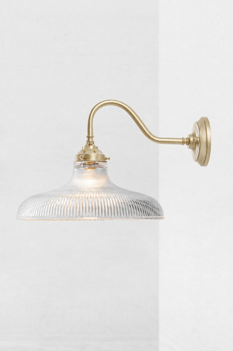 Large clear glass shade with holophane detailing, paired with a gold/brass gooseneck wall sconce. 