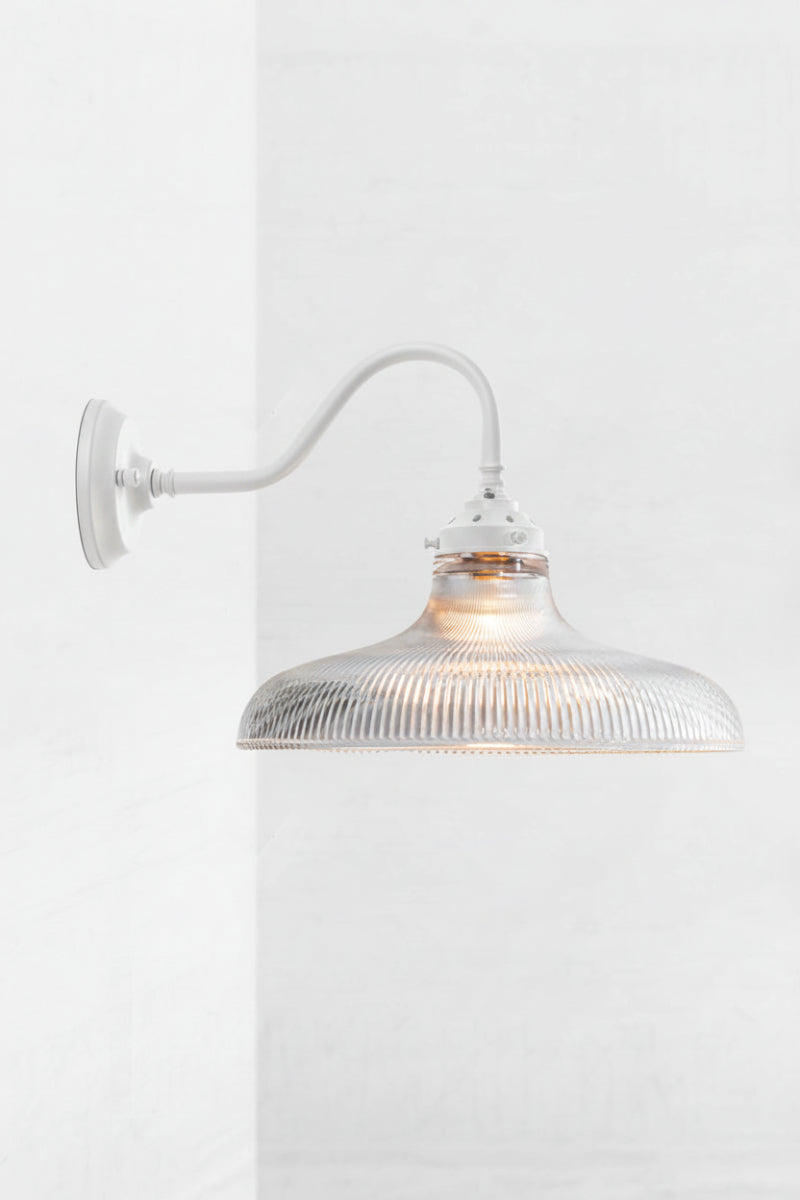 White goodeneck wall sconce paired with a large clear glass open shade with holophane detailing. 