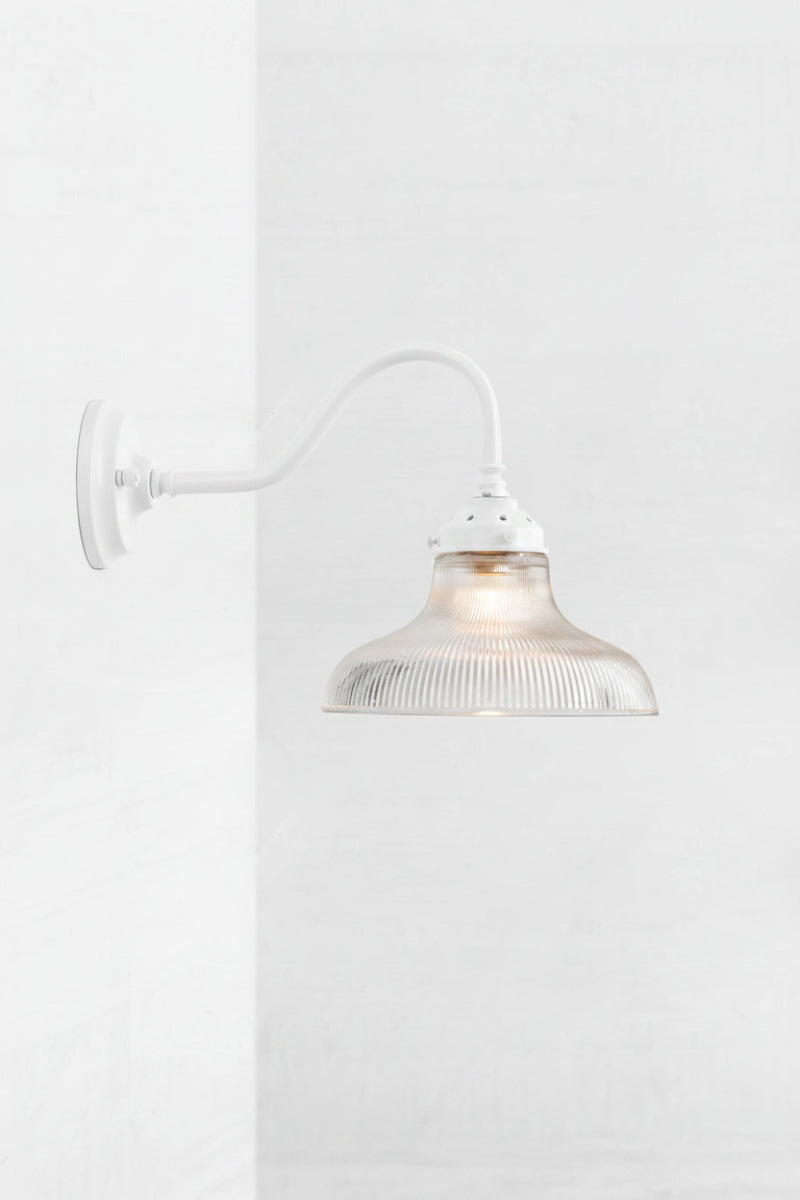 White gooseneck wall sconce arm, paired with a small clear glasss shade with holophane detailing. 