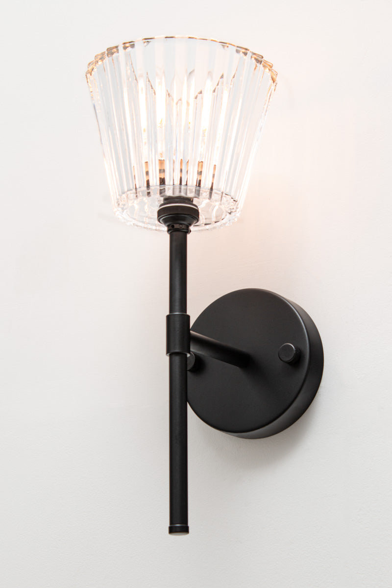 Angled view of black Davis Glass Stem Wall Light with tapered clear fluted glass shade.