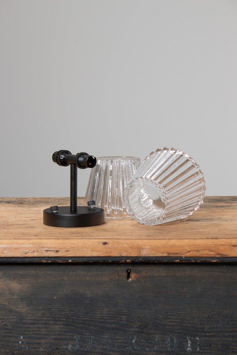 Davis Glass Double Light Wall Sconce with clear fluted glass shades and black fixture displayed on timber surface