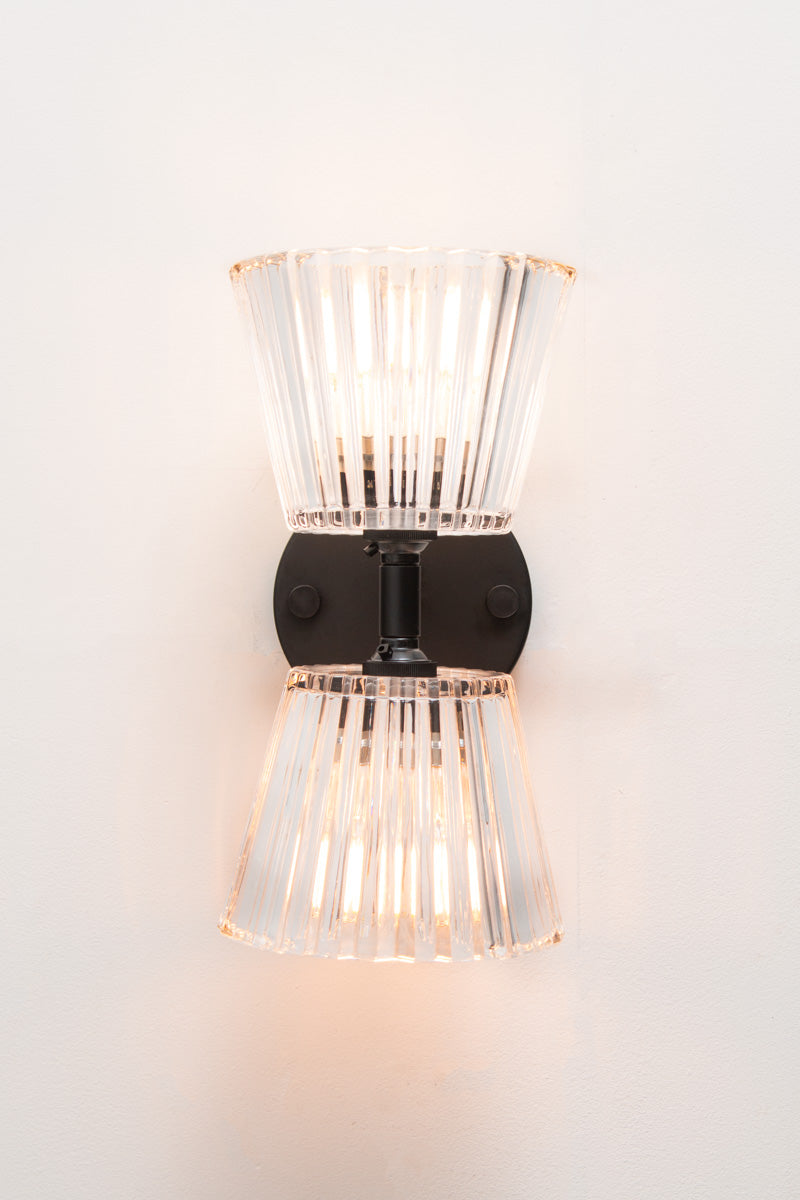 Davis Glass Double Light Wall Sconce in black with two clear vertically fluted glass shades illuminated