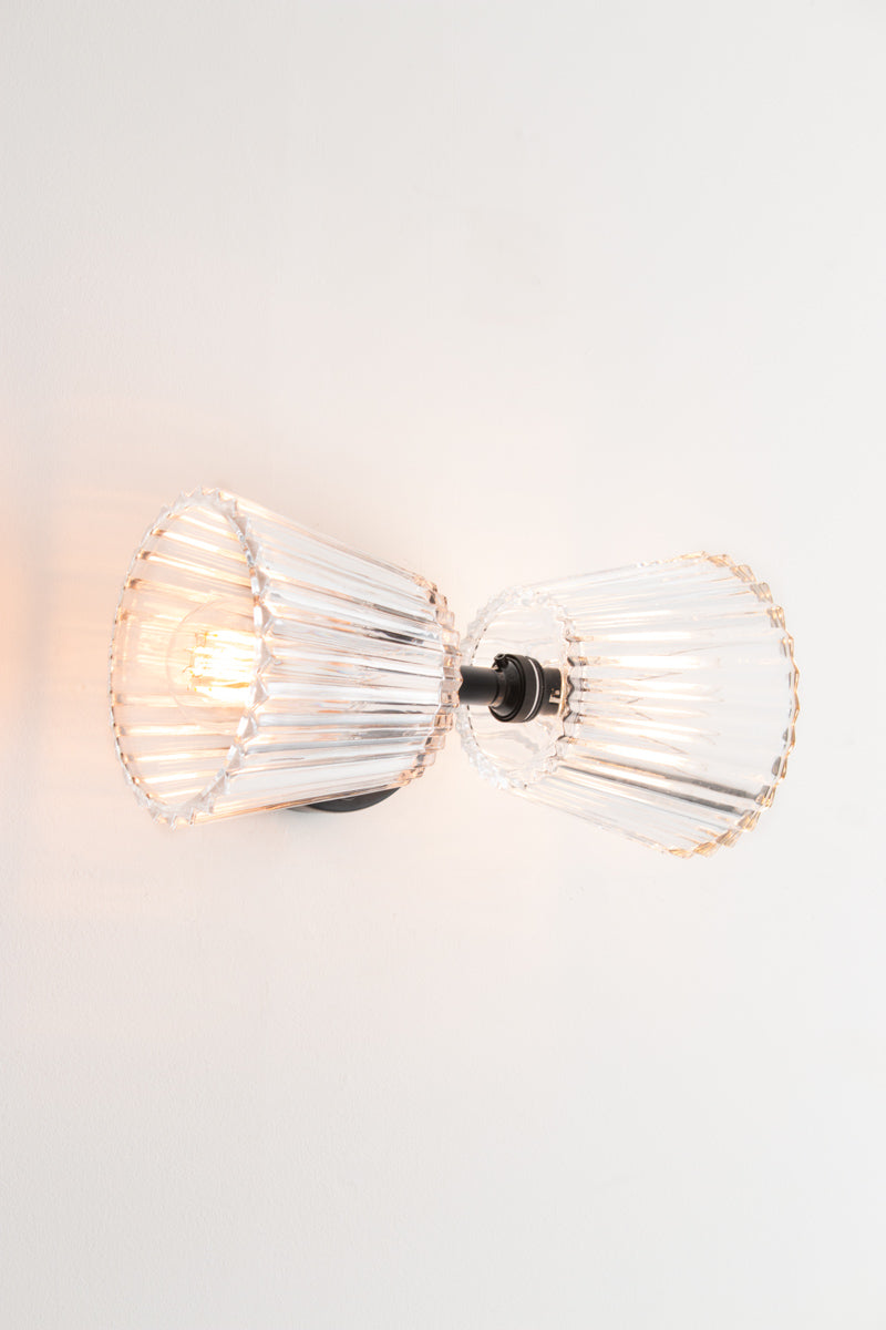 Davis Glass Double Light Wall Sconce installed horizontally with black fixture and two clear fluted glass shades