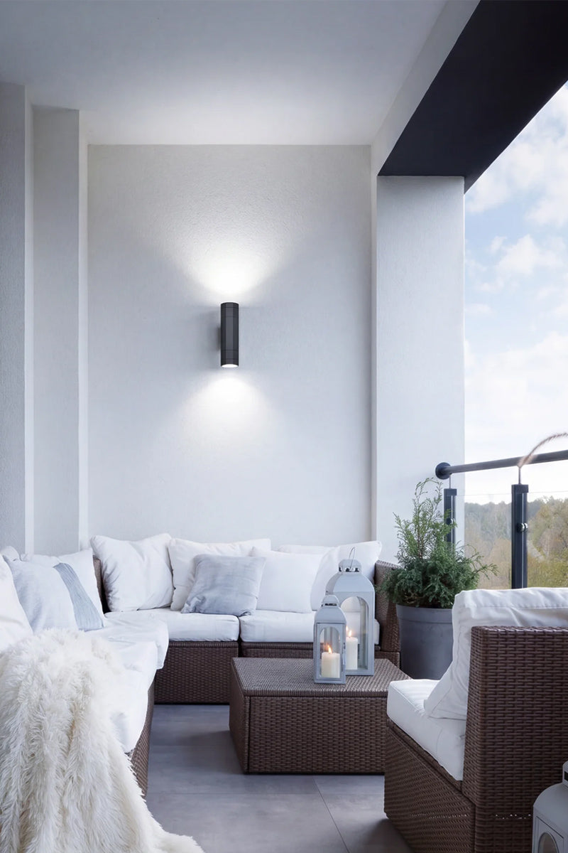 Black up down exterior spotlight on a balcony wall above outdoor lounge seating