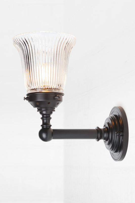 Vintage and industrial wall light. With a small clear holophane glass shade an black brass wall sconce facing up. 