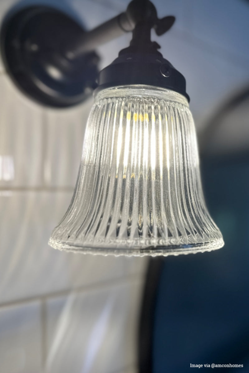 Customer image of a clear ribbed glass shade with a black steel wall sconce. 