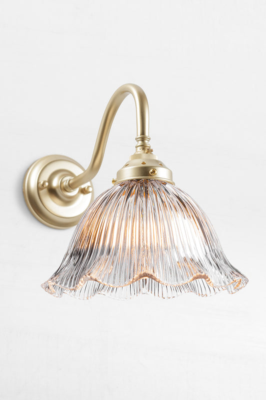 Gold/Brass gooseneck wall arm with a clear reeded, frill edged shade. 