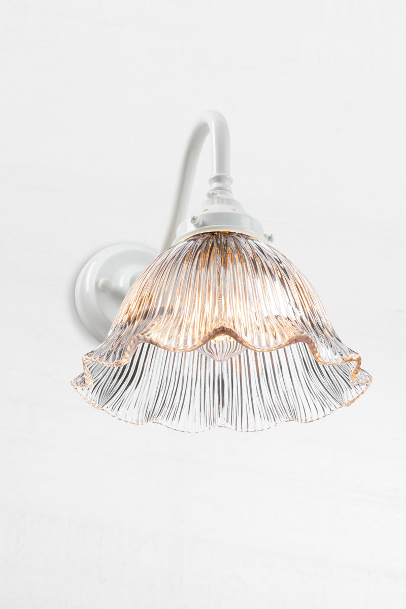 White gooseneck wall arm with a clear reeded, frill edged shade. 