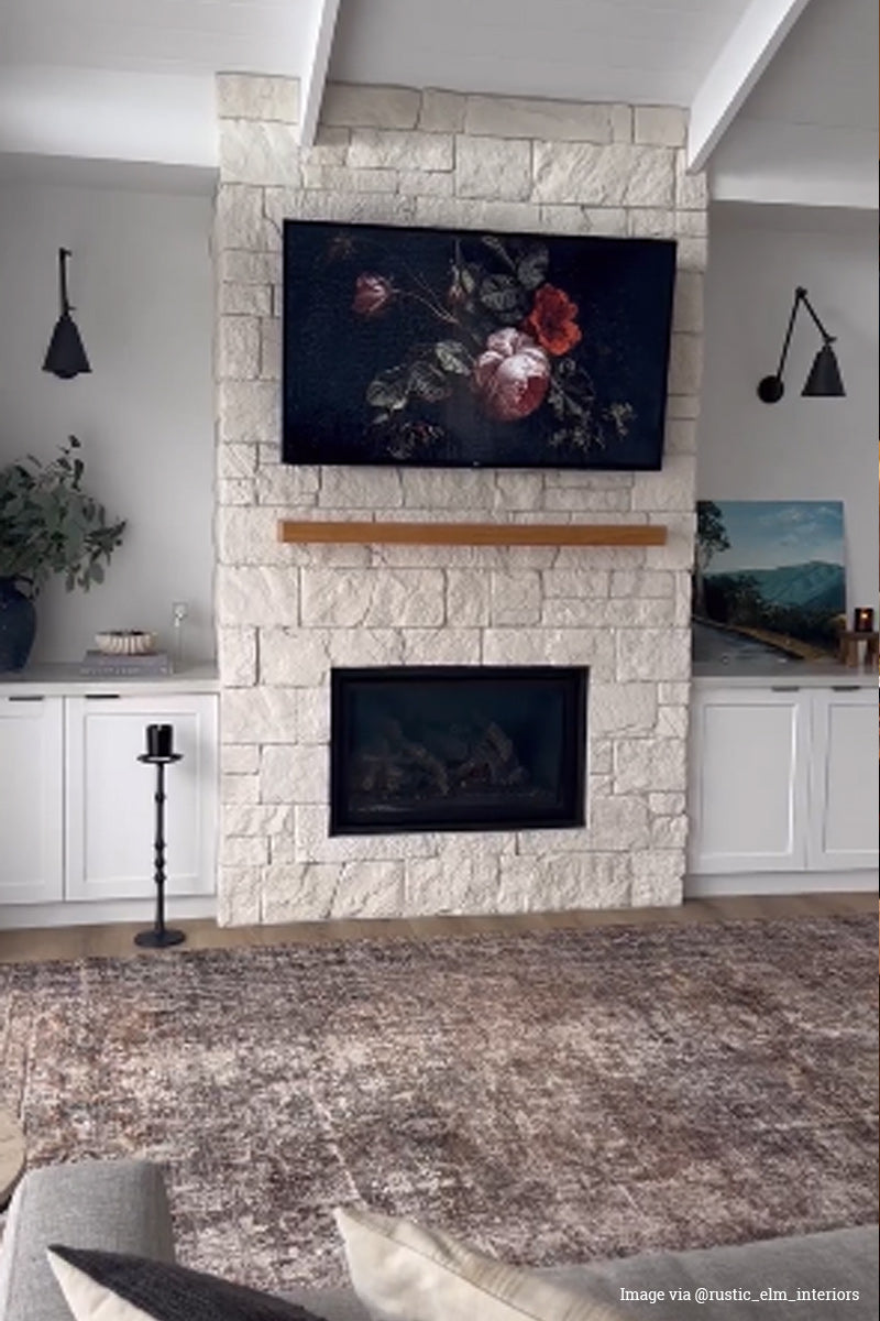 Two double arm wall lights with elongated cone shades in antique bronze, either side of a stone fireplace. 